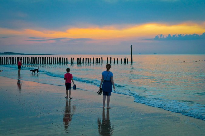 Kinder am der Nordsee, auf der linken Seite eine Frau mit Hund