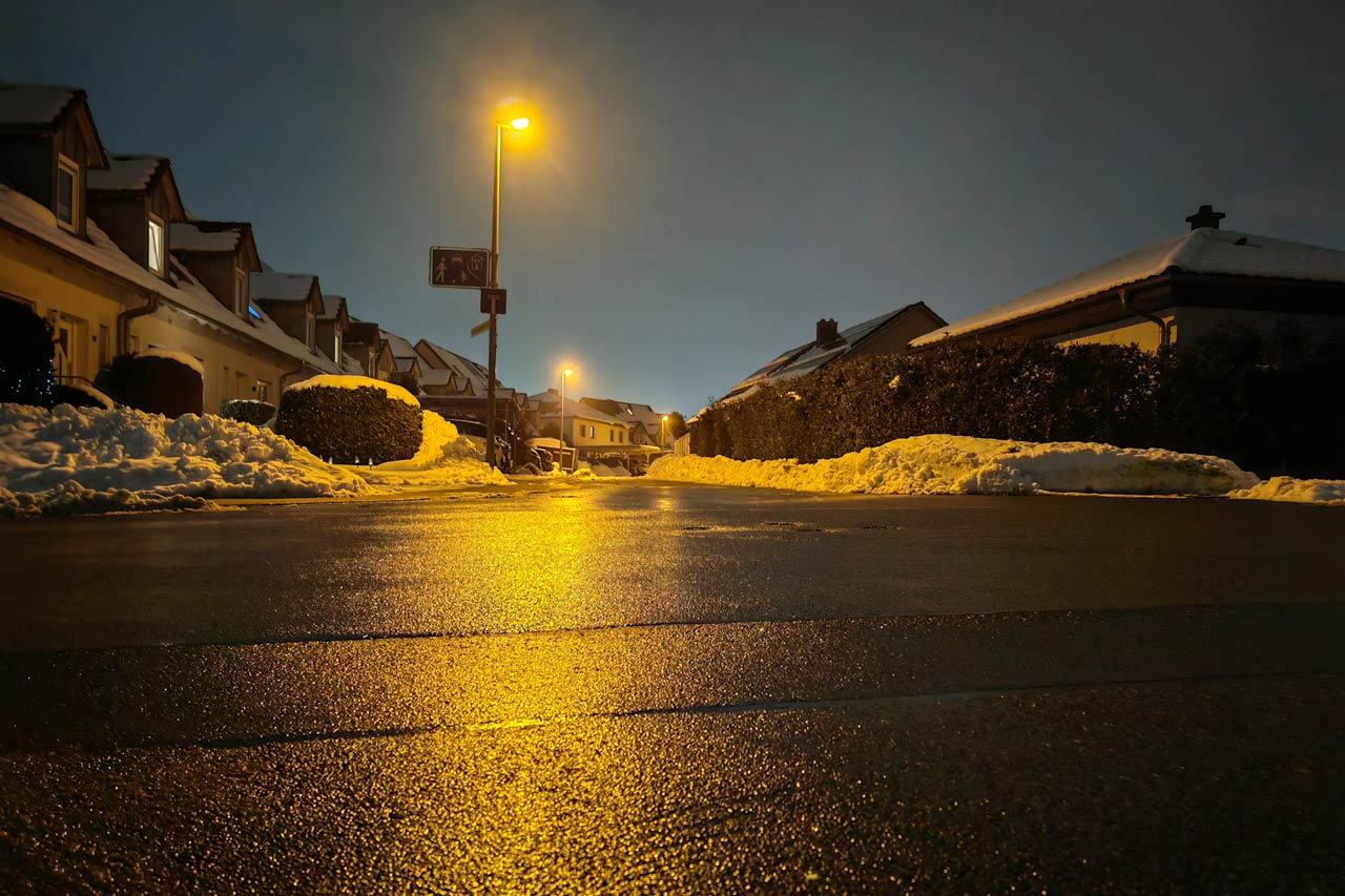 Gelbes Licht spiegelt sich auf der nassen Straße in einer Winternacht